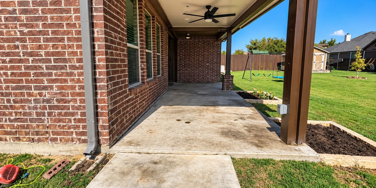 Before: original patio surface beside a brick home
